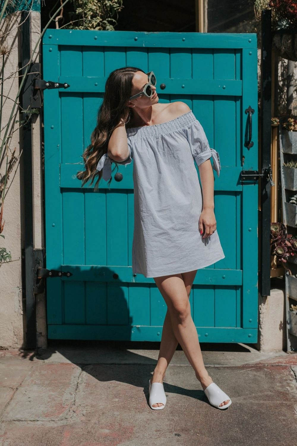 Woman in a pale dress standing against a blue door
